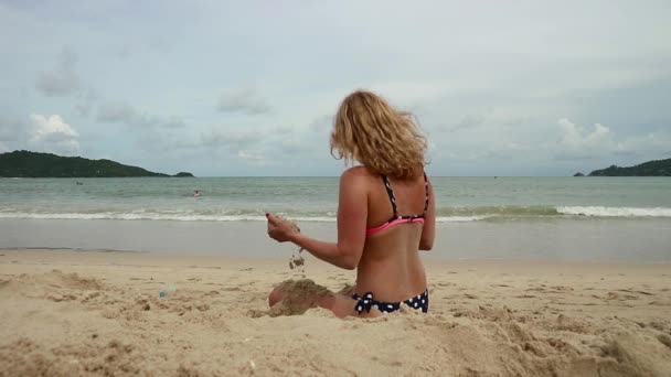 Vacker smal kvinna leker med sand på exotisk strand — Stockvideo