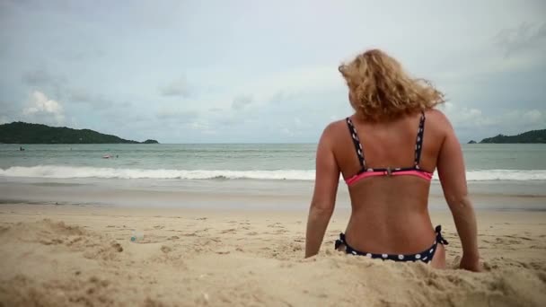 Schöne schlanke Frau ruht sich an einem sonnigen Sandstrand aus — Stockvideo