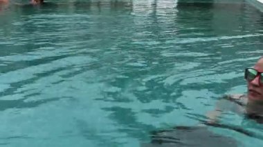 Güzel mutlu genç kadın gülümseyerek ve Otel havuzunda rahatlatıcı güneş gözlüğü