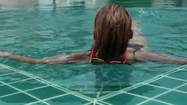 Mooie gelukkig jonge vrouw in zonnebril glimlachend en ontspannen in het zwembad van het hotel — Stockvideo