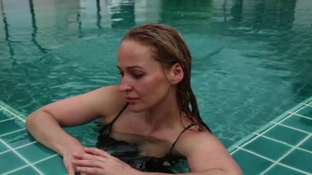 Krásná šťastná štíhlá žena v černé bikiny, s úsměvem a relaxaci v hotelovém bazénu — Stock video