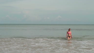 Bir deniz dalgaları ile bikinili genç kadınlarda sahiptir güneşlenme ve plaj tatil