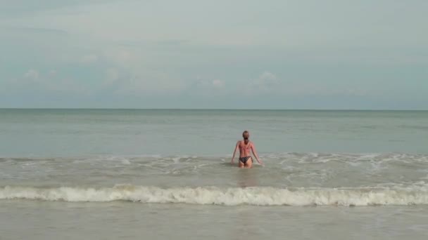 Fiatal nő a bikini, a tenger hullámok élvezi a napozás és a tengerparti nyaralás — Stock videók