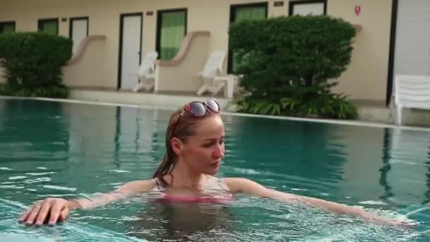 Молодая женщина в солнечных очках расслабляется и медленно плавает в бассейне — стоковое видео