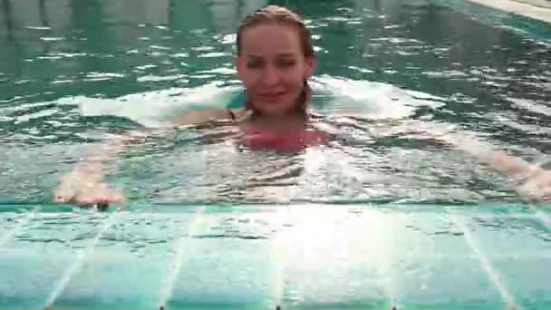 Jeune femme relaxante et nage lentement dans la piscine — Video