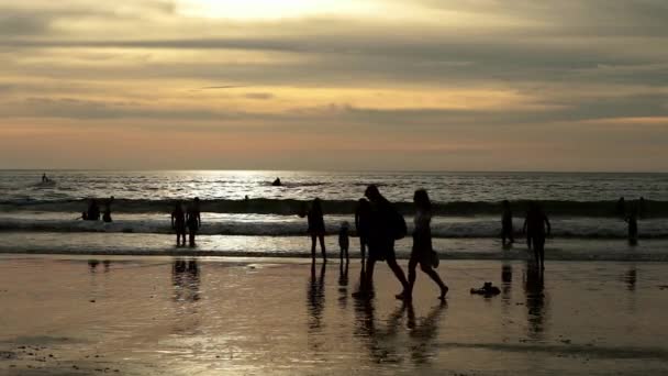 Gün batımında yaz sahilde yürürken insan siluetleri — Stok video