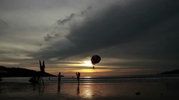 Silhouetten van mensen lopen op het strand van de zomer bij zonsondergang — Stockvideo