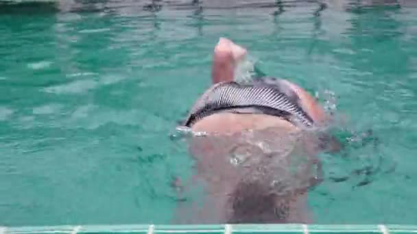 Милая девочка-подросток, играющая в веселое плавание в бассейне отеля — стоковое видео