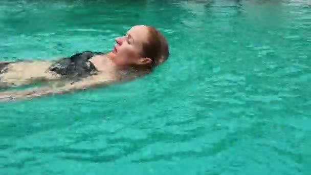 Стройная женщина в бикини расслабляющая и купающаяся в бассейне отеля. летние каникулы — стоковое видео