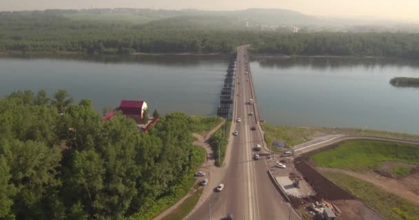 Flybilde. Bro med trafikk over elven på en solrik dag i småbyen. 4K – stockvideo