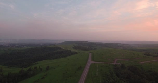 Luchtfoto. lange en bochtige weg door groene heuvels met landschap van het platteland. luchtverontreiniging rond de industriestad. 4k — Stockvideo