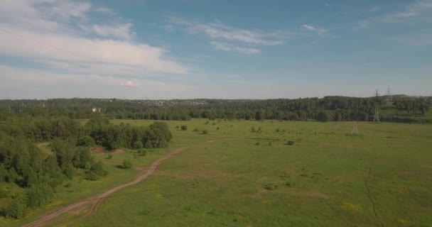 Luchtfoto. landelijke weg tussen velden en elektrische hoog-voltage ondersteunt. de weg van het platteland tussen de groene veld. 4k — Stockvideo