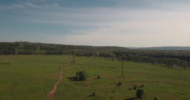 Vista aérea. estrada rural entre campos e suportes elétricos de alta tensão. estrada rural entre campo verde. 4K — Vídeo de Stock