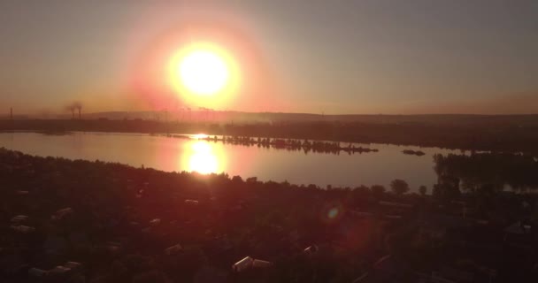 Вид с воздуха. закат над озером с небольшим городом на берегу. Промышленный завод на горизонте. 4K — стоковое видео