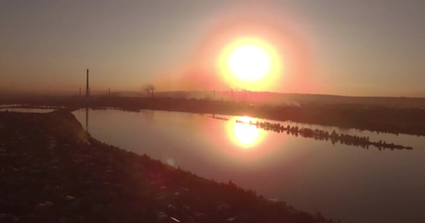 Luchtfoto. zonsondergang boven het meer met kleine stad op een oever. Fabrieksinstallatie op een horizon. 4k — Stockvideo