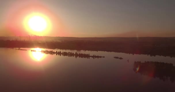 Luchtfoto. zonsondergang boven het meer met kleine stad op een oever. Fabrieksinstallatie op een horizon. 4k — Stockvideo