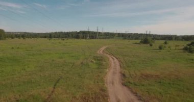 Havadan görünümü. kırsal yol alan ve elektrik yüksek gerilim destekler arasında. yeşil alan arasındaki kırsal yol. 4k