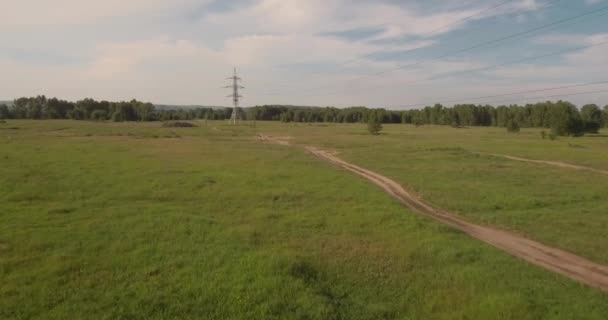 Vista aérea. camino rural entre campos y soportes eléctricos de alto voltaje. camino rural entre campo verde. 4K — Vídeo de stock