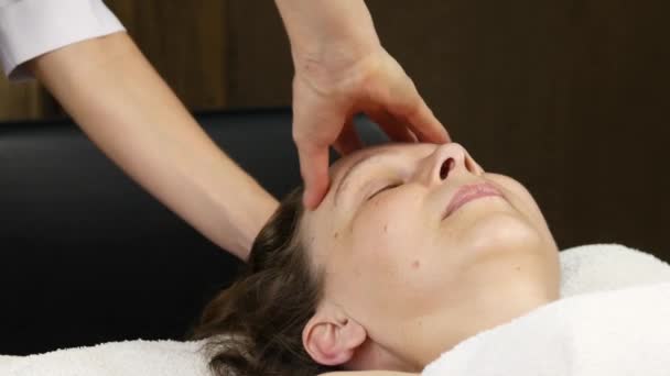 Mujer recibiendo masaje en la cabeza en el centro de spa. doctora haciendo masaje facial. 4K — Vídeo de stock