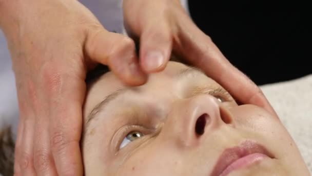 Женщина получает массаж головы в спа-центре. женщина-врач делает массаж лица. 4K — стоковое видео