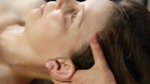 Head massage at spa center. client enjoys the services of a massage therapist — Stock Video