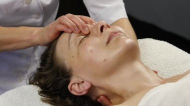 kadın doktor istemciye anti-aging masaj yapıyor. kadın plastik yüz masaj spa saton sahiptir. 4k