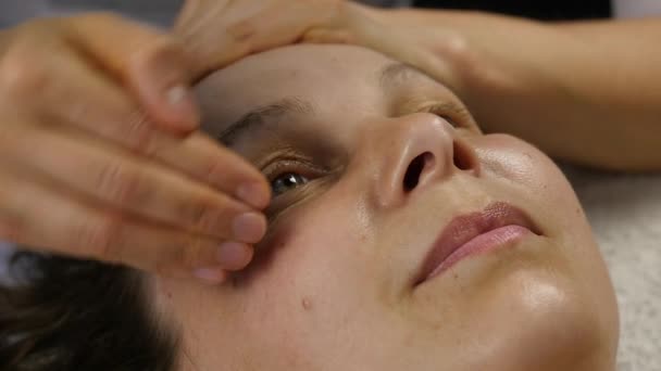 Masaż twarzy z tworzywa sztucznego w spa saton. Kobieta cieszy się z usług profesjonalnego masażysty. zwolnionym tempie — Wideo stockowe
