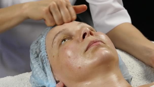 Dokter perempuan melakukan anti-penuaan pijat untuk klien. Wanita menikmati pijat wajah plastik di saton spa. 4K — Stok Video
