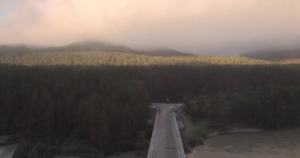 Vista aérea. puente sobre el río de montaña sobre el que nace y flota la niebla. 4K — Vídeo de stock