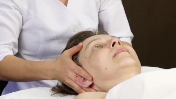 Head massage at spa center. client enjoys the services of a massage therapist — Stock Video