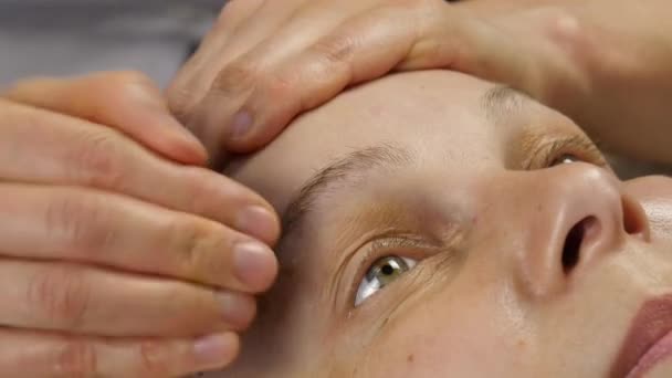Жінка отримує масаж голови в спа-центрі. жінка-лікар робить масаж обличчя. 4-кілометровий — стокове відео