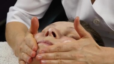 spa merkezinde masaj koltuğu alan kadın. kadın doktor yüz masaj yapıyor. 4k