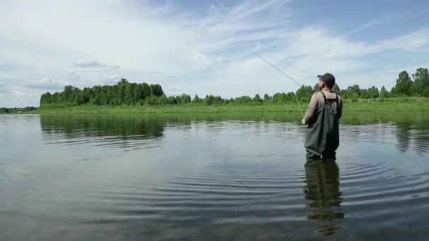 Pescador alegre pesca en aguas tranquilas cerca de la orilla — Vídeo de stock