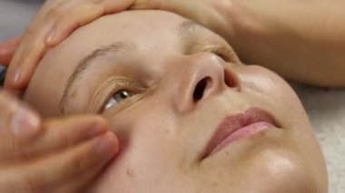 kadın doktor istemciye anti-aging masaj yapıyor. kadın plastik yüz masaj spa saton sahiptir. 4k