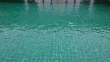 Orta yaşlı adam rahatlatıcı ve yavaş yavaş otel yüzme havuzunda yüzüyor.