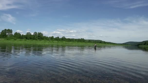 Joyful fisherman is fishing in calm river water near the shore — Stock Video