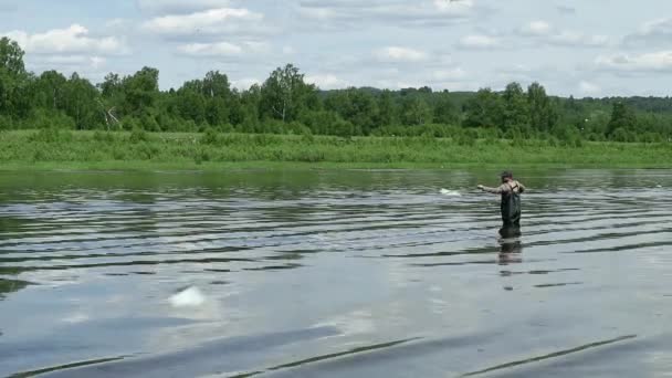 Fiskare som fiskar i en lugn flod på morgonen. Mannen i fiskeredskap stending i en flod och kastar ett metspö — Stockvideo