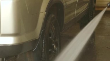 Adam bir oto yıkama hizmetinde bir araba yıkama. Araba su jeti yıkama ile temizledim. ağır çekim