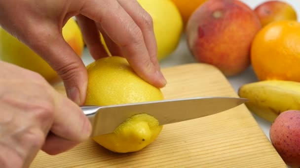 Woman slices the citrus fruit on a wooden cutting board with variety of fruits around. Weight loss and dieting concept. slow motion — Stock Video