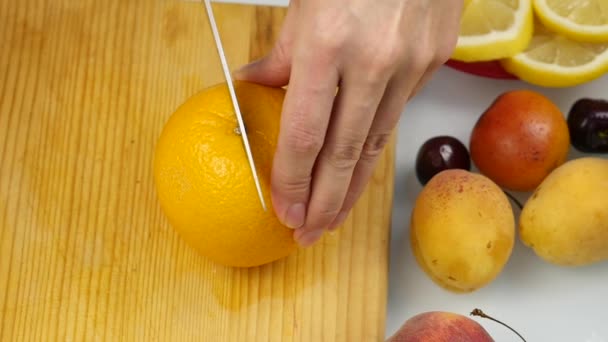 Femme délicate tranchant des fruits frais à l'orange sur une planche à découper pour salade ou jus. Perte de poids et concept de régime. au ralenti — Video