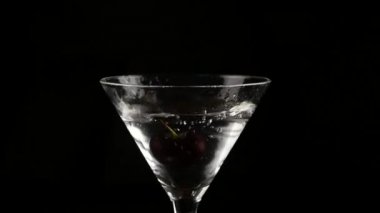 kiraz bir bardak alkol karanlık bir arka plan üzerinde kokteyl ile içine atılmış. bir kokteyl ve parti kavram hazırlar. ağır çekim