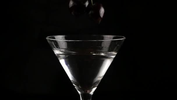 Kers in een glas met alcohol cocktail op een donkere achtergrond gegooid. bereidt een cocktail en party concept. Slow motion — Stockvideo