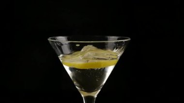 limon parçası bir bardak alkol karanlık bir arka plan üzerinde kokteyl ile içine atılır. ağır çekim