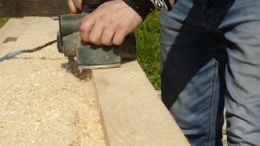 planya makinesi bir ahşap üzerine çalışan adam. Planer farklı taraftan cips sinek