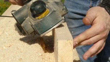 planya makinesi bir ahşap üzerine çalışan adam. Planer farklı taraftan cips sinek