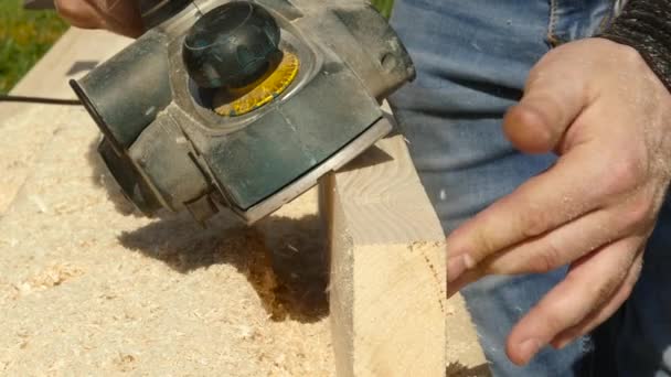 Hombre trabajando en una máquina cepilladora de madera. Las virutas vuelan en diferentes lados de la cepilladora — Vídeos de Stock