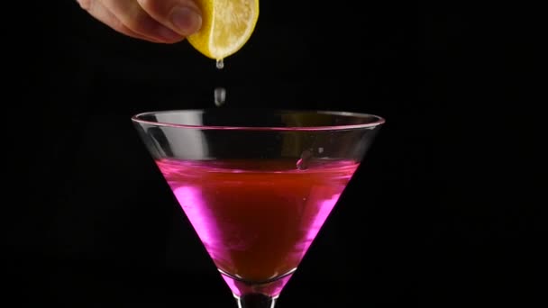 Close-up of woman squeeze yellow lemon on alcohol cocktail into the glass. slow motion — Stock Video