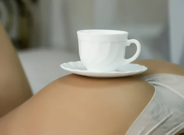 Sexy femme nue relaxant sur un lit avec une tasse de thé sur ses fesses — Photo