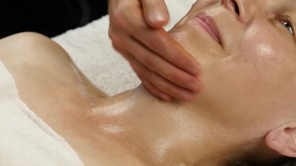 Vrouwelijke arts anti-veroudert massage aan client doen. vrouw geniet kunststof gezicht massage in de spa saton. 4k — Stockvideo