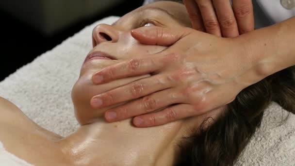 Женщина-врач делает антивозрастной массаж клиенту. женщине нравится пластический массаж лица в спа-сатоне. 4K — стоковое видео